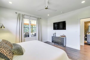A bedroom with a bed, a dresser, a television, and a ceiling fan.