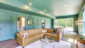 A modern living room with a sectional sofa, a coffee table, and a billiards table.