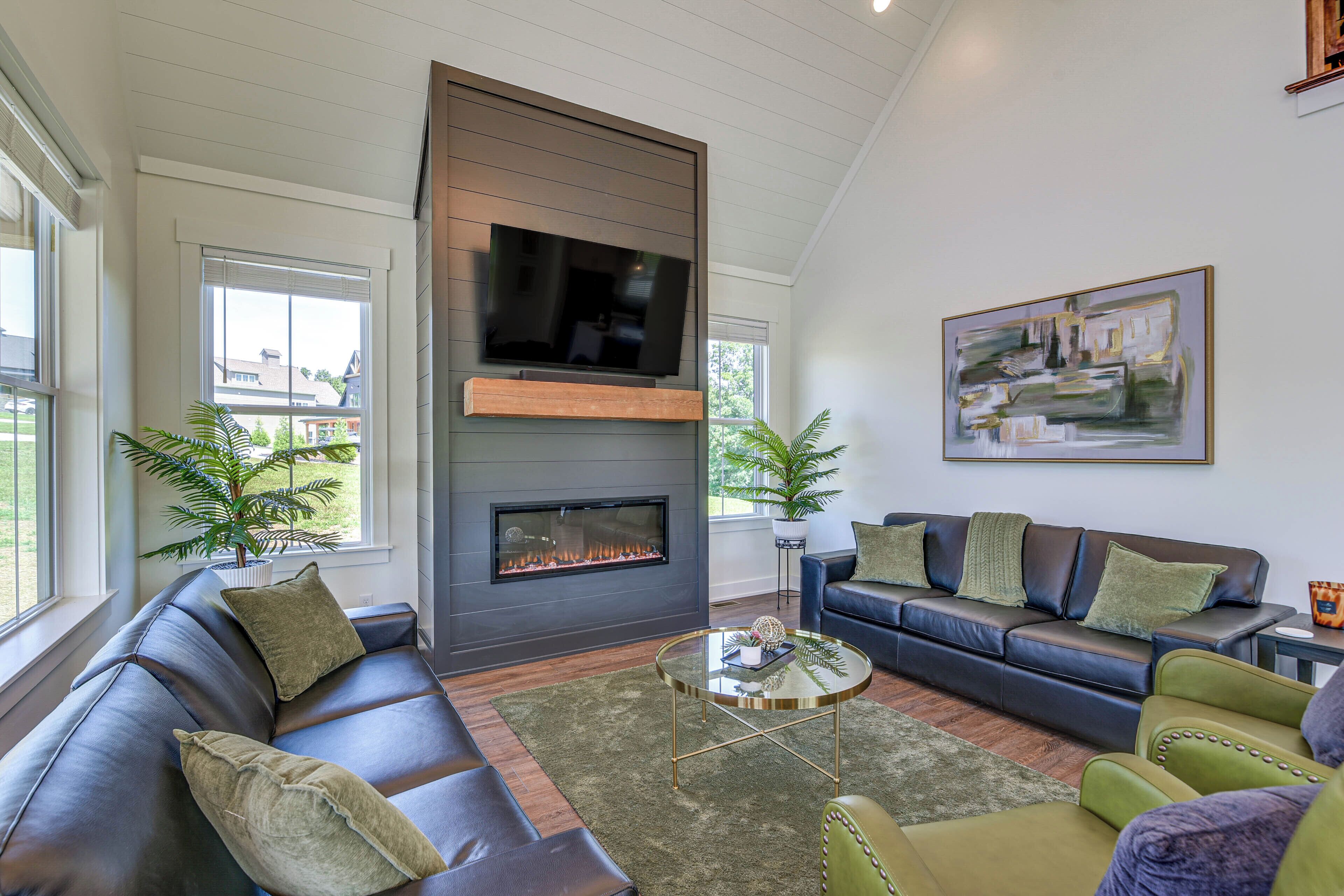 A modern living room with a fireplace, leather sofas, a coffee table, and a large painting on the wall.