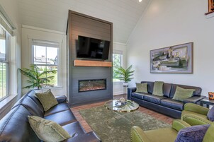 A modern living room with a fireplace, leather sofas, a coffee table, and a large painting on the wall.