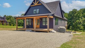 Een huis met twee verdiepingen, een overdekte veranda en een grindpad.