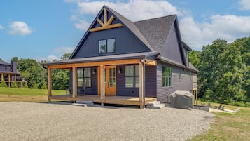A two-story house with a covered porch and a gravel driveway.