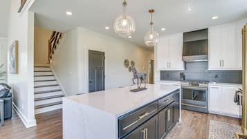A modern kitchen with a marble island, stainless steel appliances, and pendant lighting.