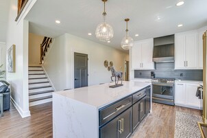 A modern kitchen with a marble island, stainless steel appliances, and pendant lighting.
