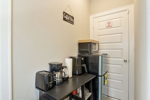 Eine Küchenzeile mit Kaffeemaschine, Toaster, Mikrowelle und Kühlschrank.
