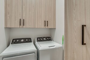 A laundry room with two front-loading washing machines and a wooden cabinet above. - Game Room & Stunning Mtn Views! Cedar City Home (Cedar City)