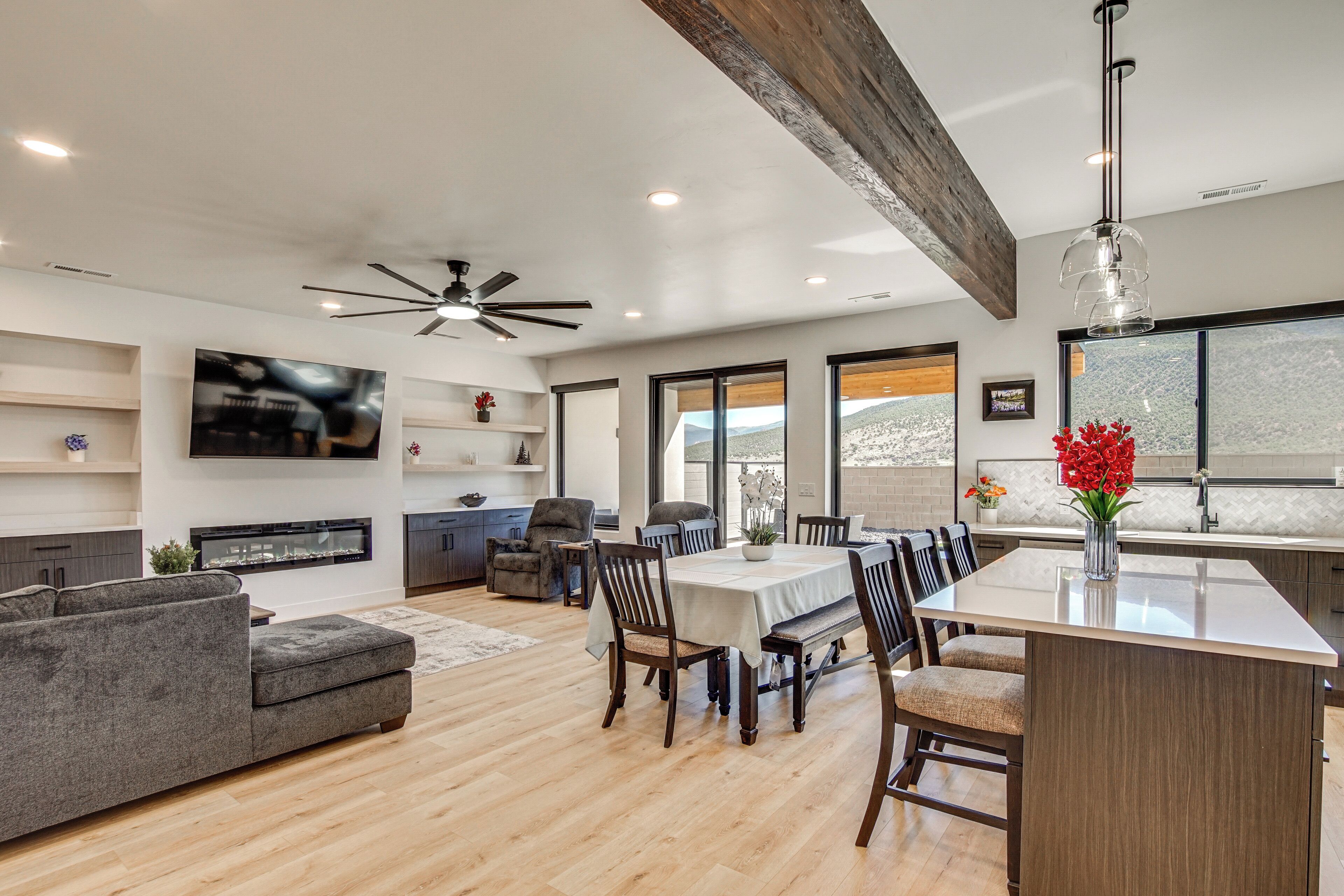 A modern kitchen with a large island, dining area with chairs, and a TV mounted on the wall.