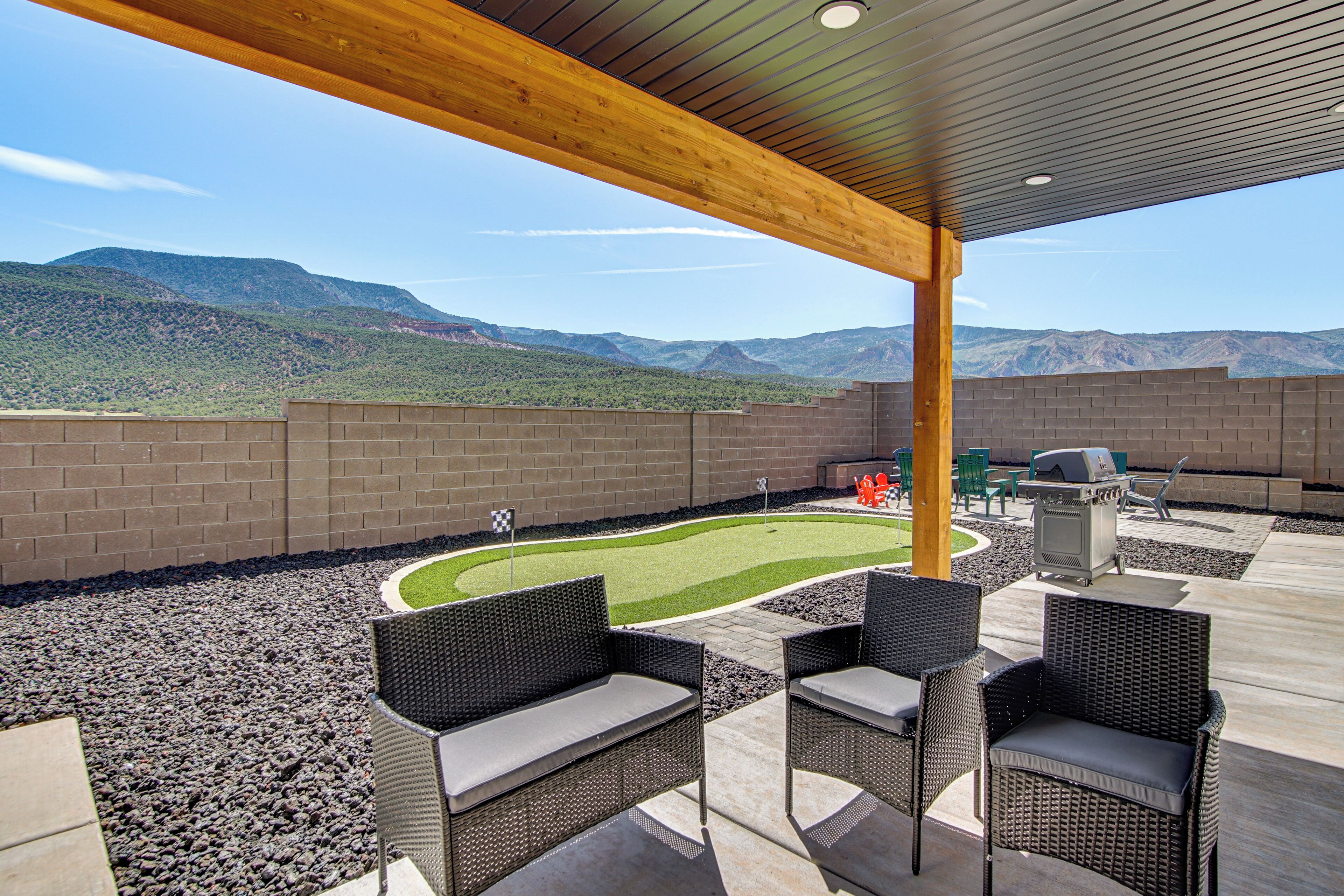 An outdoor patio with wicker furniture, a barbecue grill, and a view of mountains.