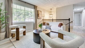Una sala de estar moderna con un sofá, una mesa de centro y un rascador para gatos.