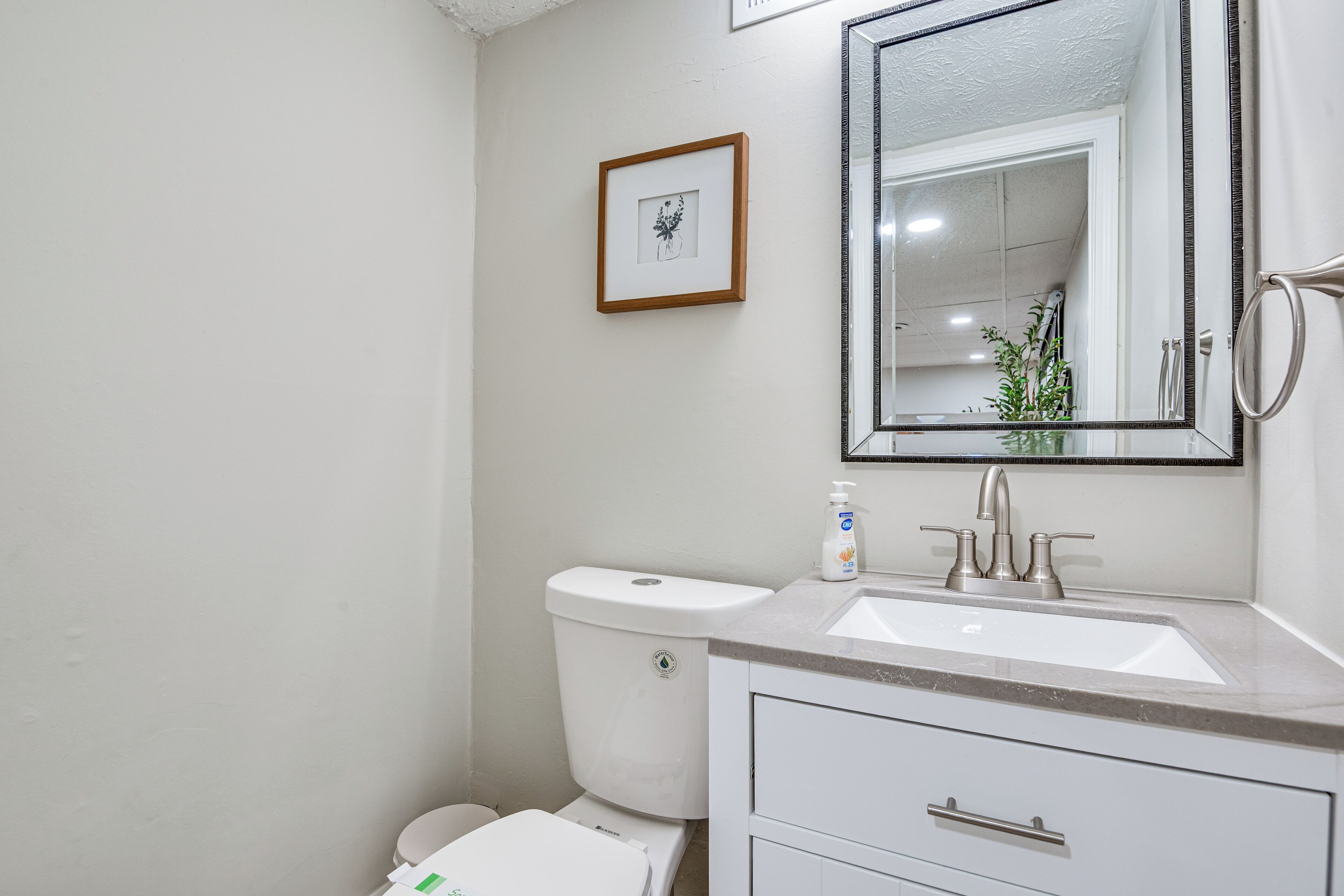 A bathroom with a toilet, sink, and mirror.