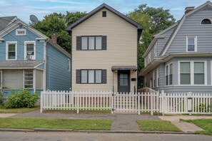 A two-story house with a white picket fence, a front door, and a small porch. - Walk to Water, Dining! Modern City Point Haven (New Haven)