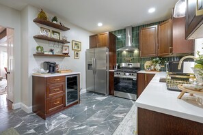 A modern kitchen with a refrigerator, oven, and stove. There are wooden cabinets and a marble floor. - Walk to Water, Dining! Modern City Point Haven (New Haven)