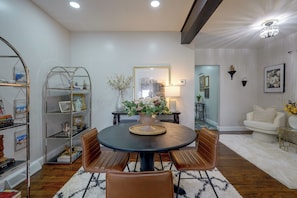 A modern living room with a round dining table, leather chairs, a bookshelf, a vase with flowers, and a framed picture on the wall. - Walk to Water, Dining! Modern City Point Haven (New Haven)