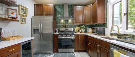 A kitchen with wooden cabinets, a stainless steel refrigerator, a stove, and a microwave.