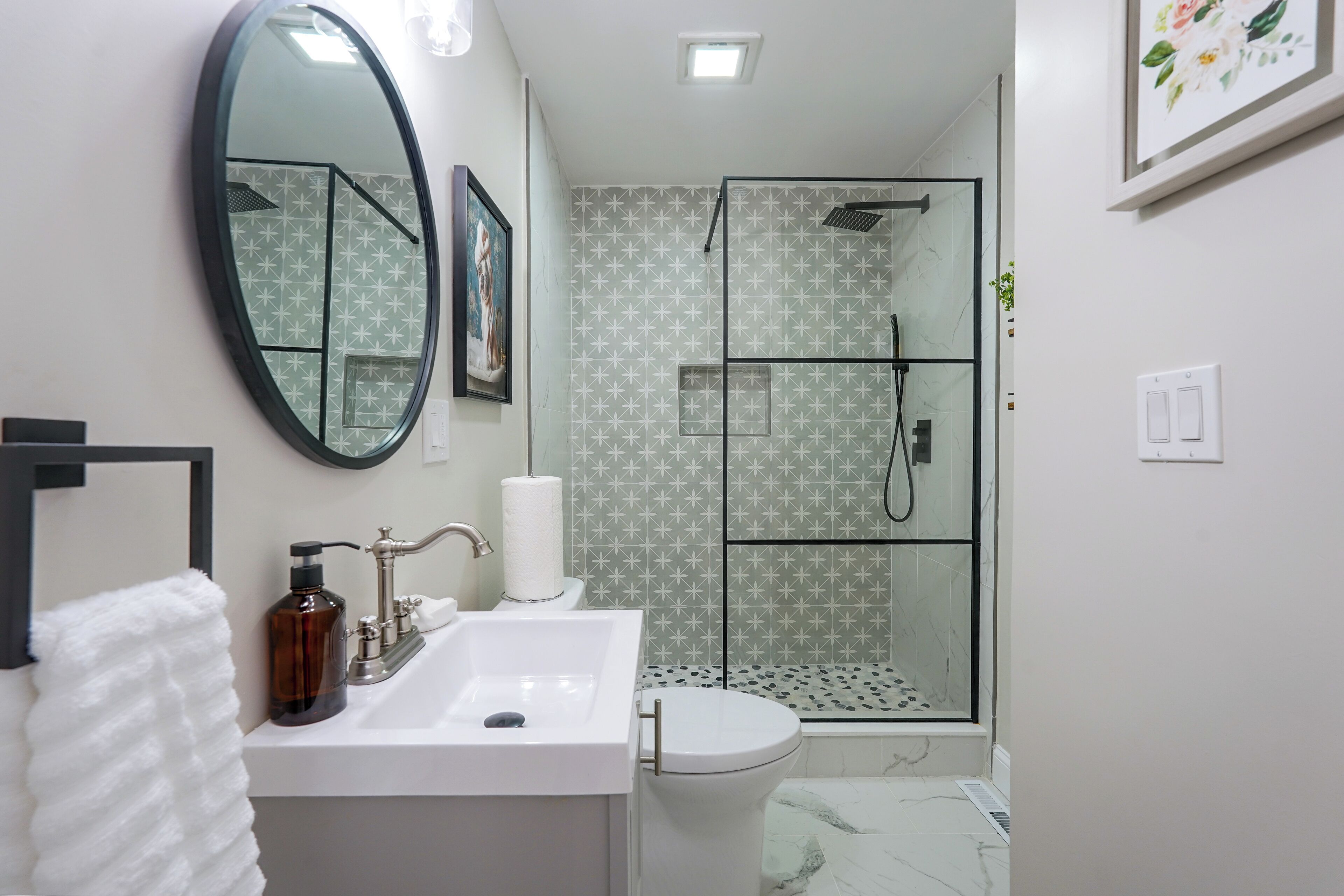 A bathroom with a white sink, a toilet, a glass shower enclosure, and a mirror.