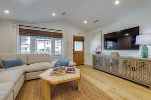 A modern living room with a sofa, coffee table, and a TV mounted on the wall. - Stroll to Redondo Beach: Modern, Coastal Gem (Redondo Beach)