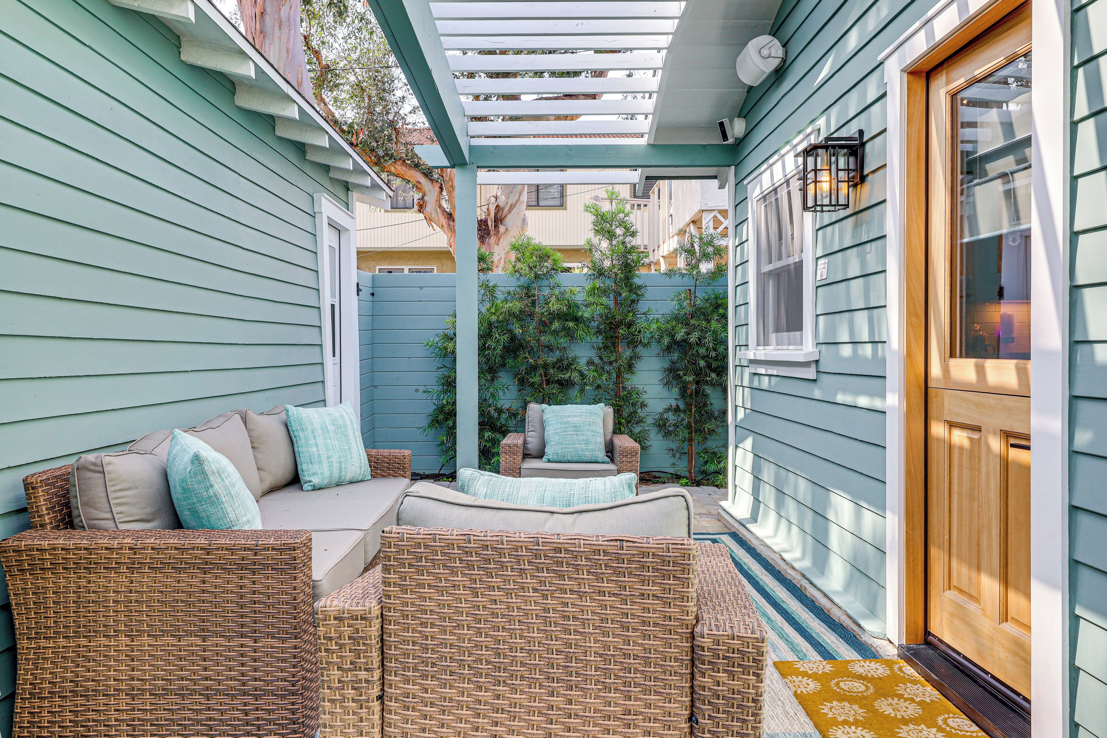 A covered patio area with wicker furniture and a wooden door.