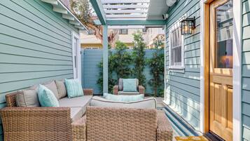 A covered patio area with wicker furniture and a wooden door.