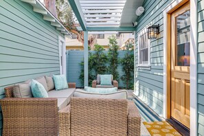 A covered patio area with wicker furniture and a wooden door.