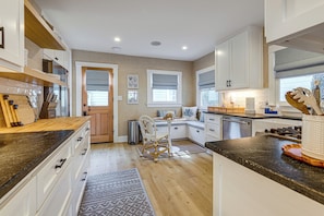 A modern kitchen with white cabinetry, a wooden countertop, and a built-in dishwasher.