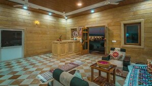 Una habitación de hotel con piso a cuadros, paredes de madera, un mostrador de recepción, un sofá y una cama.