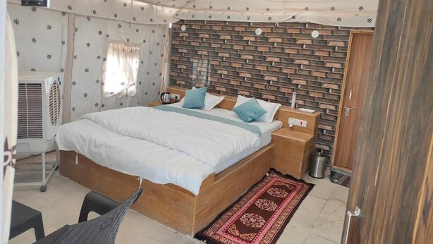 Un dormitorio con cama, mesitas de noche, cabecero de madera, ventana con cortinas y un radiador.