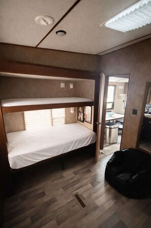 A bunk bed with a mattress, a black bag, and a window with blinds. - Trailer at the Peters Pond on beautiful Cape Cod! (Sandwich)