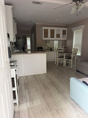 Une cuisine moderne avec des meubles blancs, un îlot central et un coin repas avec des chaises.