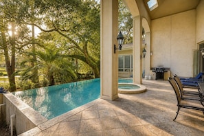 A pool area with a hot tub, outdoor seating, and a view of trees. - 9 Beach Lagoon | Lagoon Luxury with Infinity Pool | Walk to the Beach (Hilton Head Island)