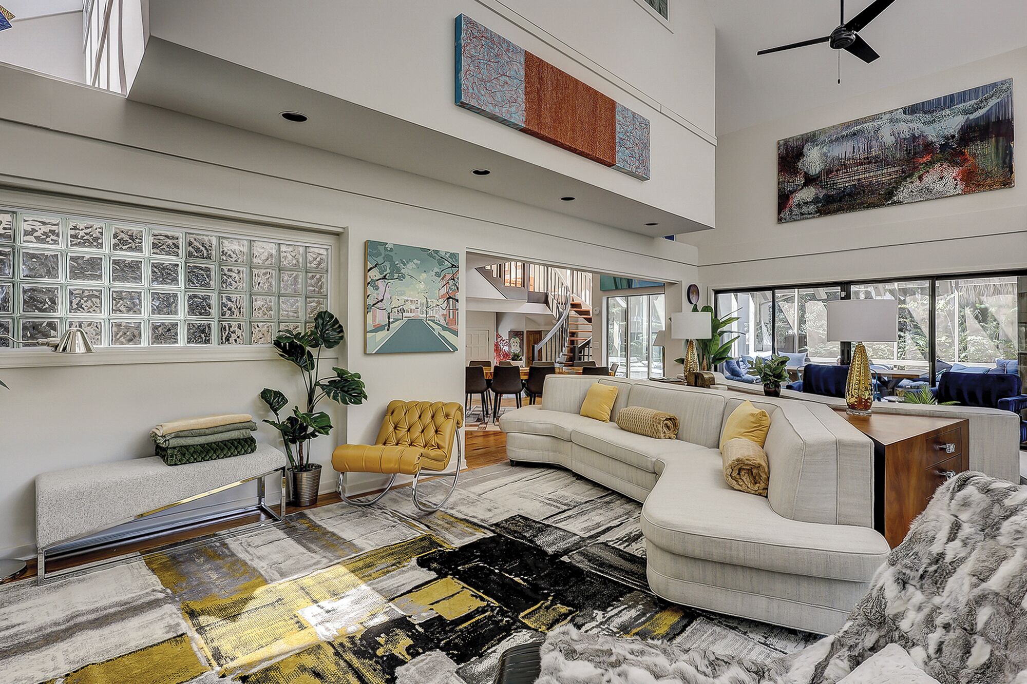 A spacious living area with a curved sofa, a coffee table, and a large window providing natural light.