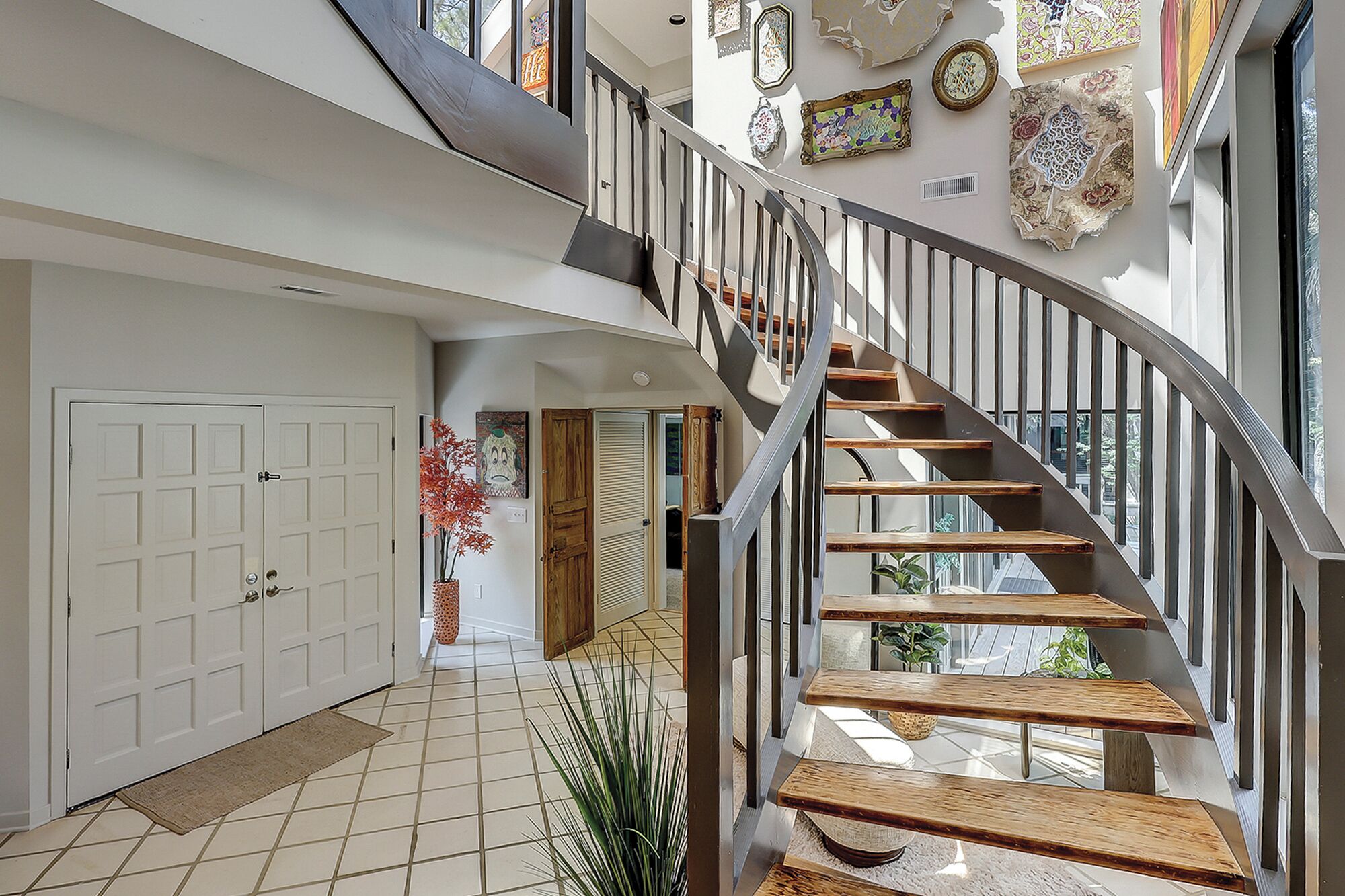 A modern interior with a curved staircase, a white door, and decorative wall art.