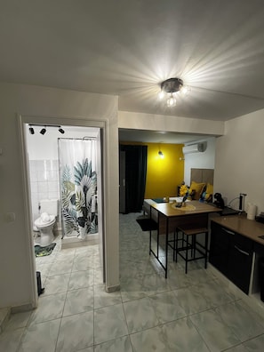 A kitchen with a dining area, a bathroom with a toilet, and a yellow wall. - 5 minutes from the beaches: Apartment in Schoelcher—Soleil d'émeraude (Schœlcher)