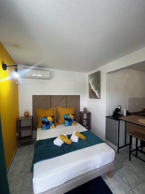 A hotel room with a bed, bedside tables, a desk, and a kitchenette. - 5 minutes from the beaches: Apartment in Schoelcher—Soleil d'émeraude (Schœlcher)