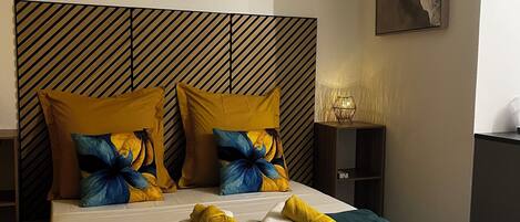 Une chambre d’hôtel avec un grand lit, deux oreillers, une table de chevet, une lampe et un tableau au mur.