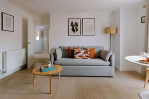 A modern living room with a grey sofa, a small round table, and a floor lamp.