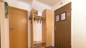 Un corridoio con una porta in legno, un appendiabiti, una mensola e un tappetino.