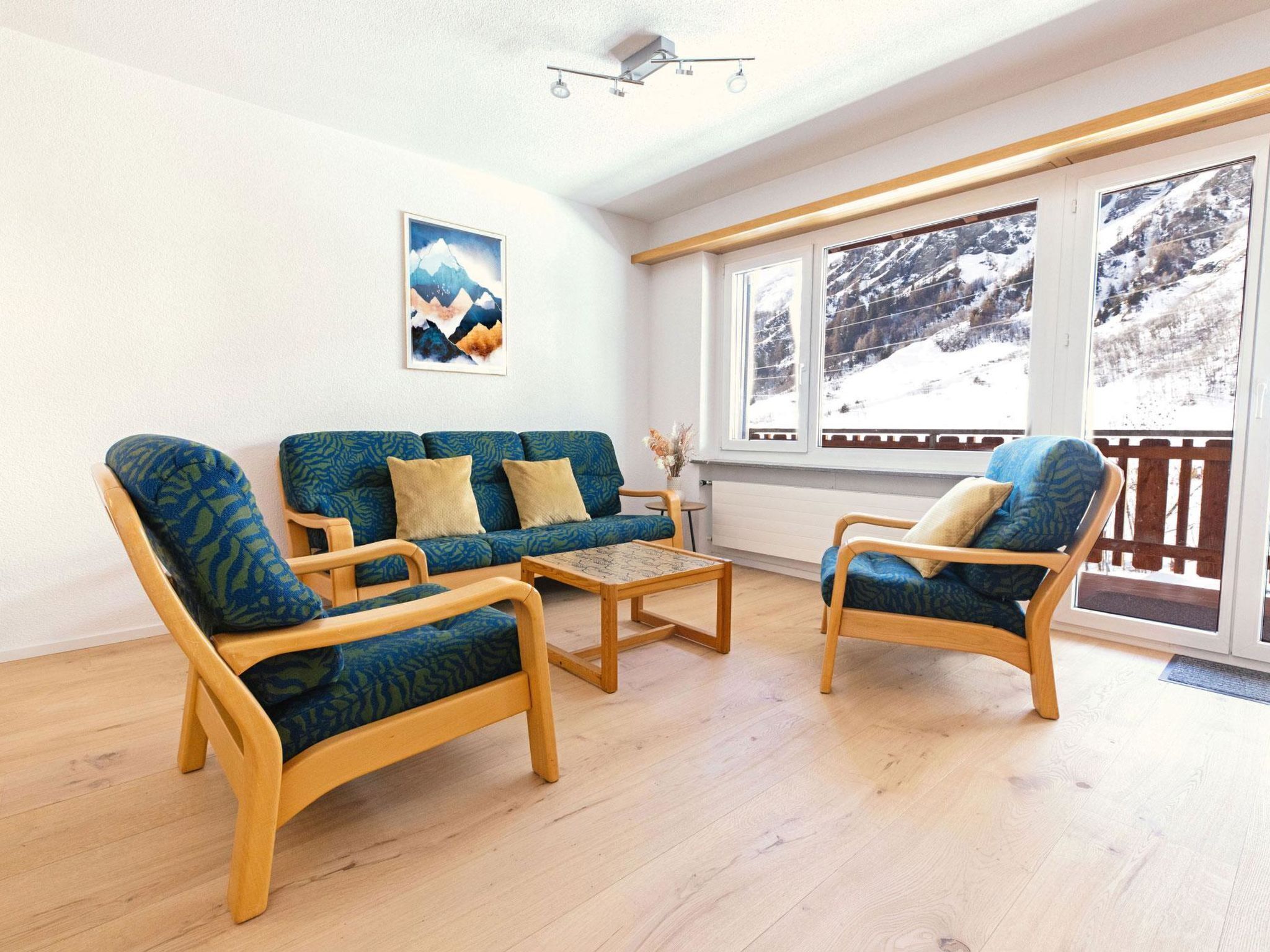 Un salon comprenant un canapé, deux fauteuils, une table basse et une grande fenêtre donnant sur un paysage enneigé.