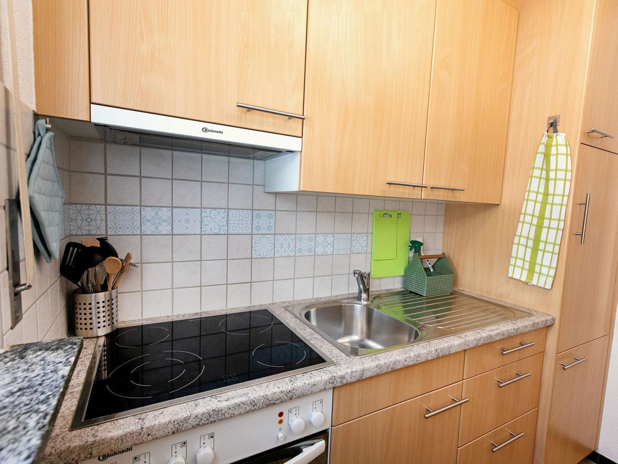 A kitchen with wooden cabinets, a built-in stove, a sink, and a green dish rack.