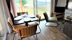 Ruokailutila, jossa on kahdelle katettu pöytä, sohva ja televisio.
