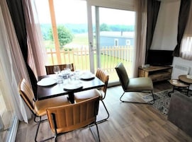 Un comedor con una mesa lista para dos personas, un sofá y un televisor.