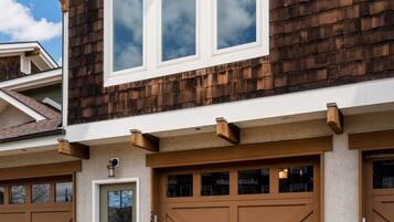 A two-story house with a brown shingle exterior, a front door, and two garage doors.