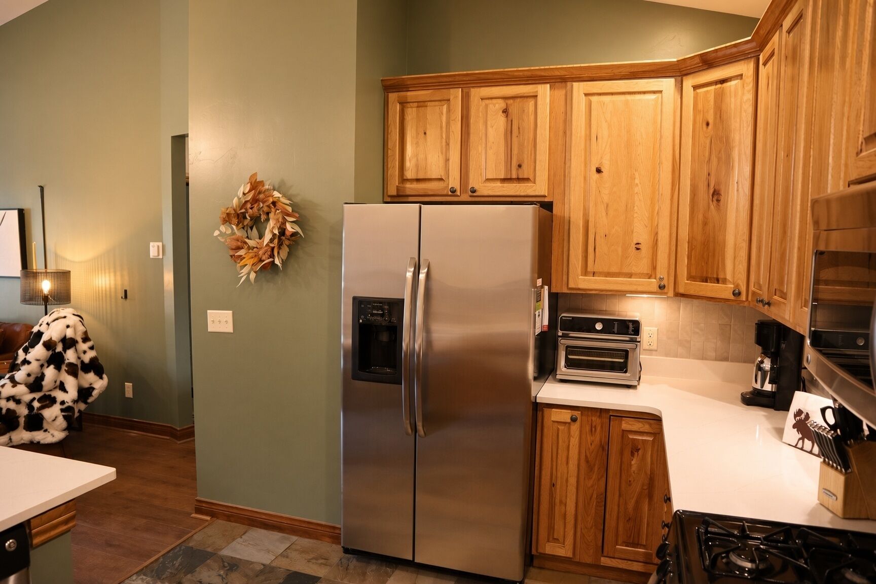 A kitchen with wooden cabinets, a stainless steel refrigerator, a built-in oven, and a gas stove.