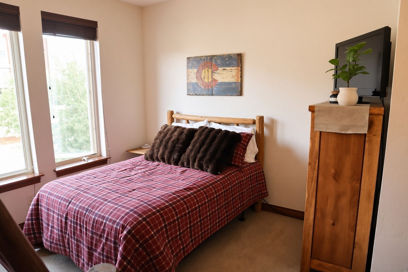 A bedroom with a bed, a nightstand, a painting, a television, and a window.