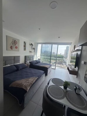 Une chambre moderne avec deux lits, un coin repas et une grande fenêtre donnant sur la ville.