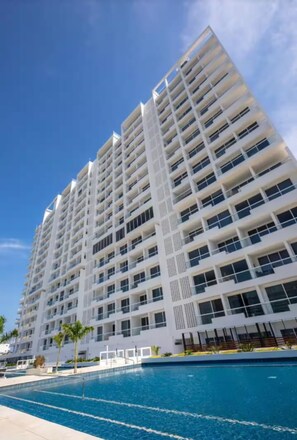 A high-rise hotel with multiple balconies, a swimming pool, and a clear blue sky. - Suite de luxe en bord de mer à Santa Marta (Magdalena)