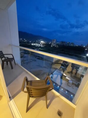 A balcony with a view of a cityscape at dusk. - Suite de luxe en bord de mer à Santa Marta (Magdalena)