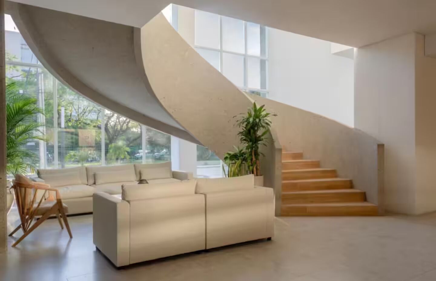 Un intérieur moderne avec un escalier en colimaçon, un canapé et une plante en pot.