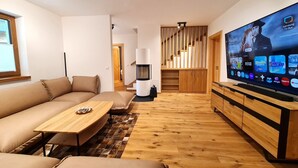 A modern living room with a sofa, coffee table, TV, and a staircase leading to another level.