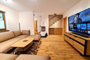 A modern living room with a sofa, coffee table, TV, and a staircase leading to another level.