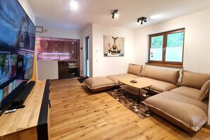 A modern living room with a wooden floor, a sofa set, a coffee table, and a TV.
